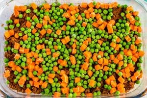 Sprinkle peas and carrots on top of beef mixture.