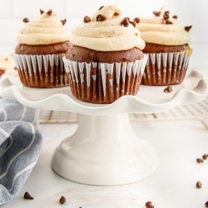 A close up picture of the finished Chocolate Peanut Butter Cupcakes on a white cake pedestal.