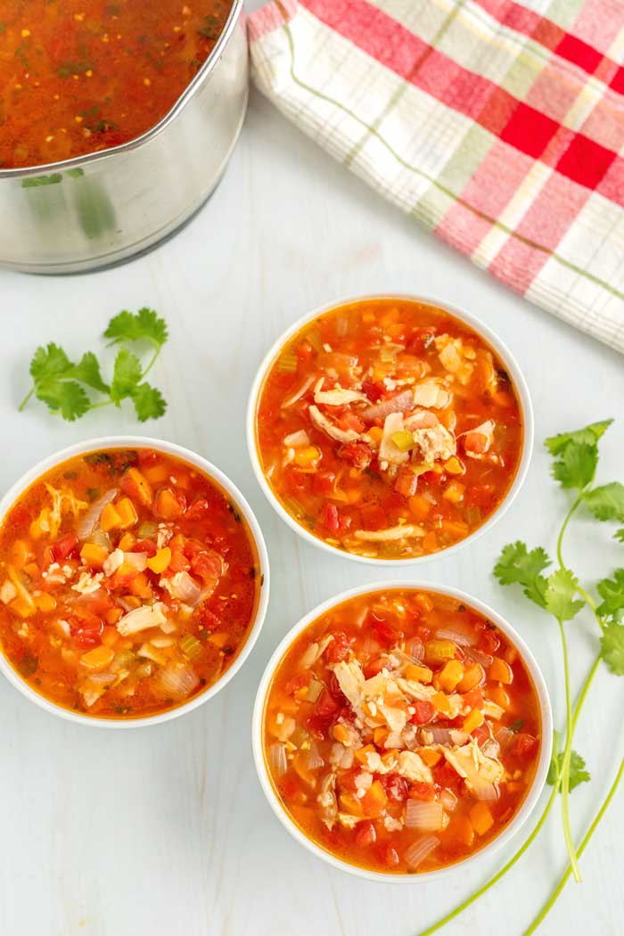 Bowls of chicken tortilla soup without topping on them.