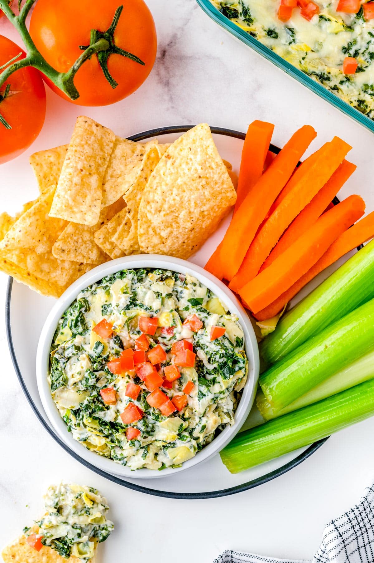 An overhead picture of the Artichoke Spinach Dip on a platter with tortilla chips and veggies.