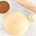 The dough on a floured surface with a rolling pin and the cinnamon sugar filling.