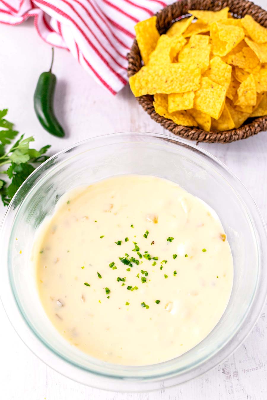 Velveeta Queso Blanco Dip in a clear bowl with a bowl of tortilla chips nearby. 