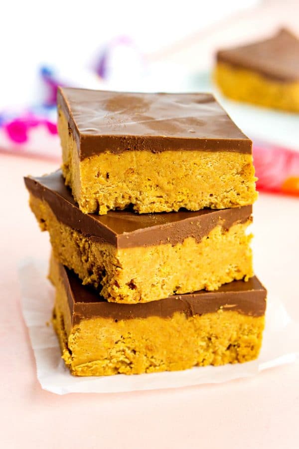 No-Bake Peanut Butter Bars in a stack with a pink background. 