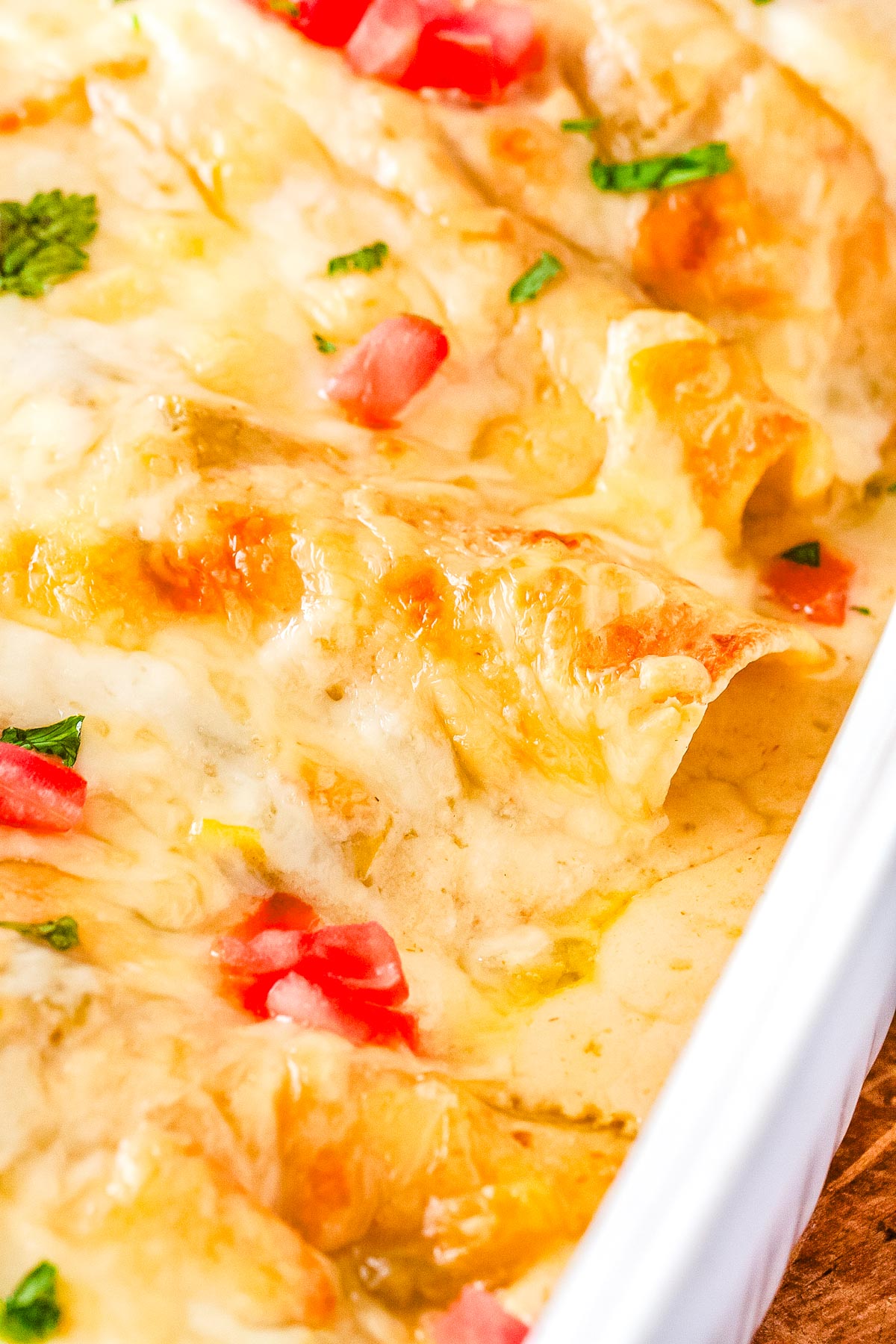 The gren Chile chicken enchiladas with sour cream in a caserole dish and swimming in a creamy green chile sauce.