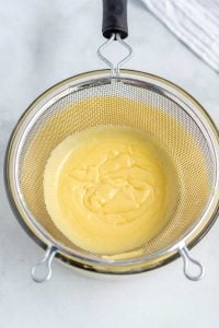 Pour the hot pastry cream through a fine mesh strainer.