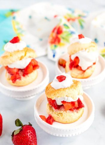 Shortcakes on pedestals with strawberries surrounding them.