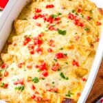 The finished Sour Cream Chicken Enchiladas Recipe in a casserole dish and garnished with chooped tomatoes and cilantro.