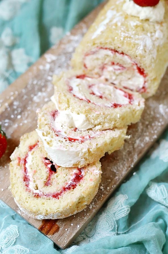A close up of slices of Strawberry Shortcake Roll Cake on a cutting board