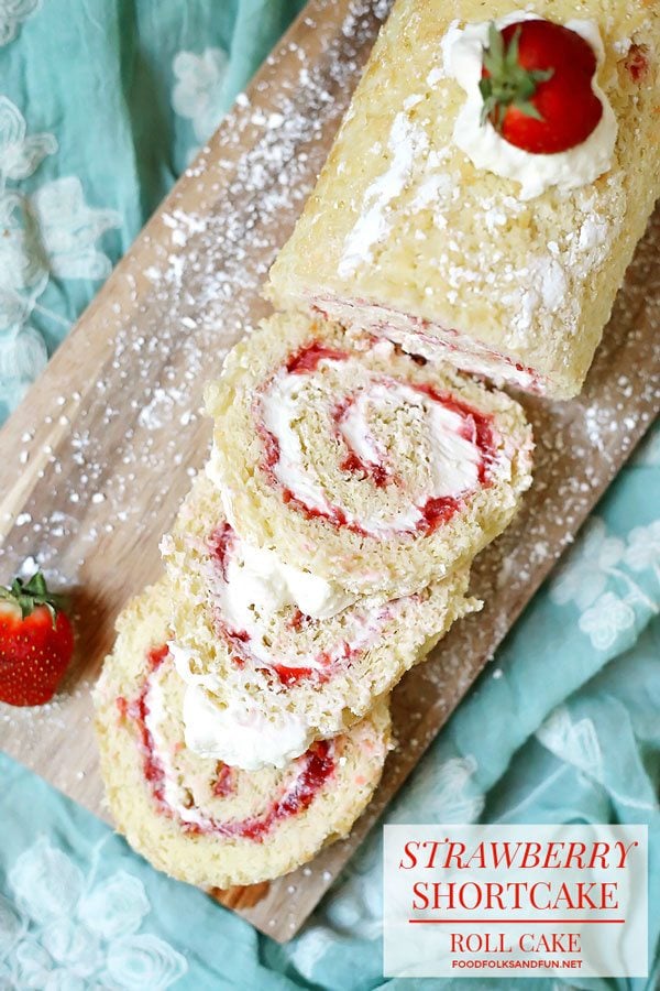 Strawberry Roll Cake on a wooden cutting board with 3 slices cut.