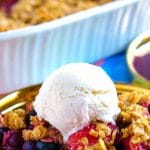 Berry crisp on a plate that is served with ice cream.