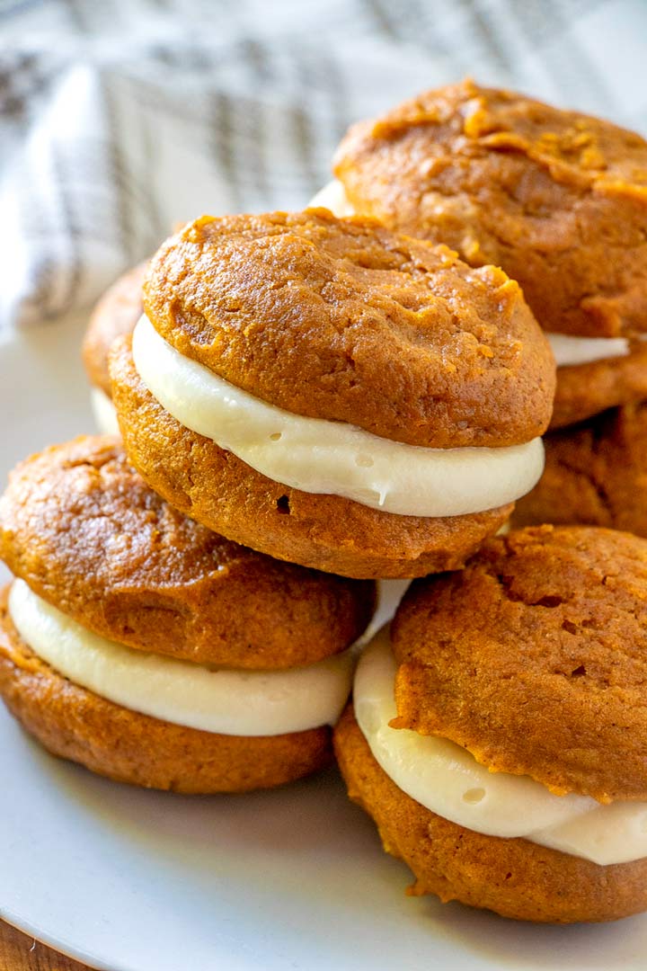 A plate of pumpkin whoopie pies stacked on top of each other.