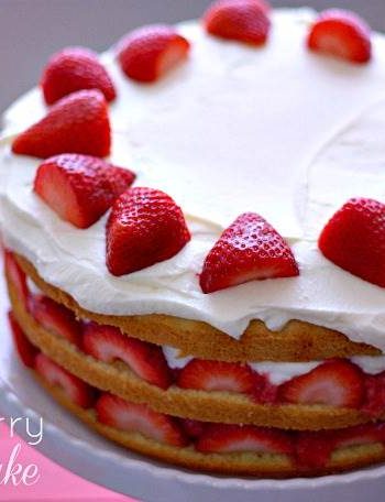A layered strawberry cream cake on a cake stand with text overlay for Pinterest