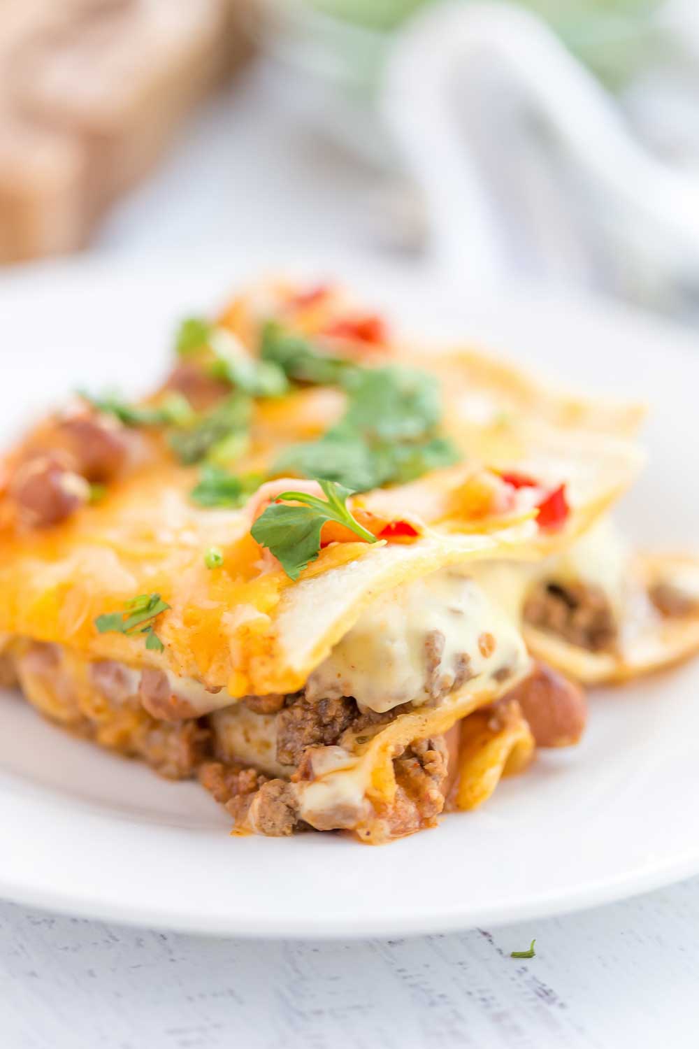 Mexican Lasagna with stacked tortillas, seasoned ground beef, beans, Rotel tomatoes, and cheese!