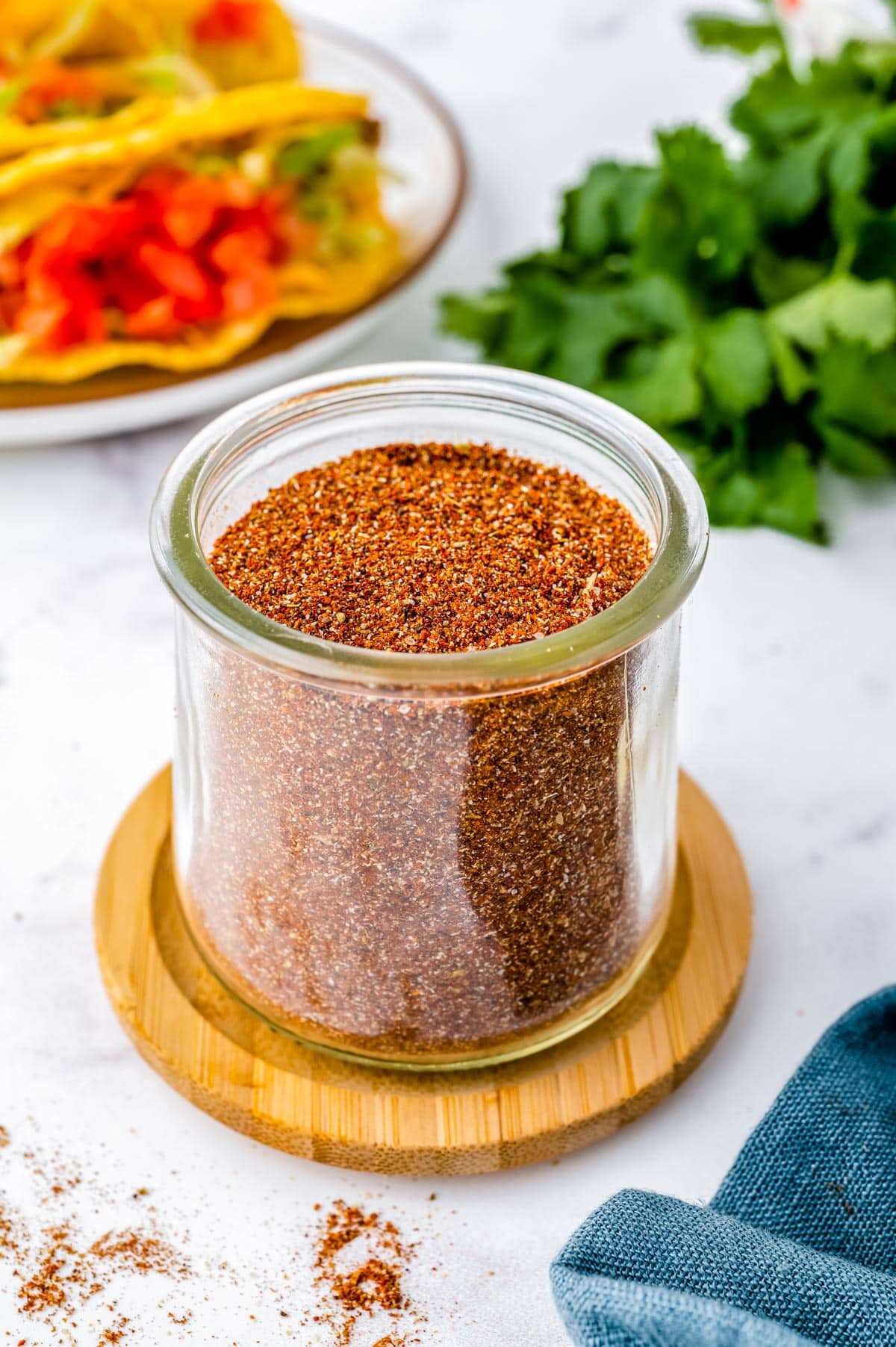 Homemade Taco Seasoning in a glass jar with tacos in the background.