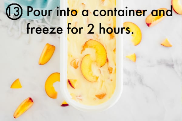 The ice cream inside an ice cream container that is garnished with fresh peaches.