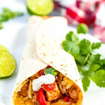 A chicken fajitas with sour cream, cheese, and salsa.