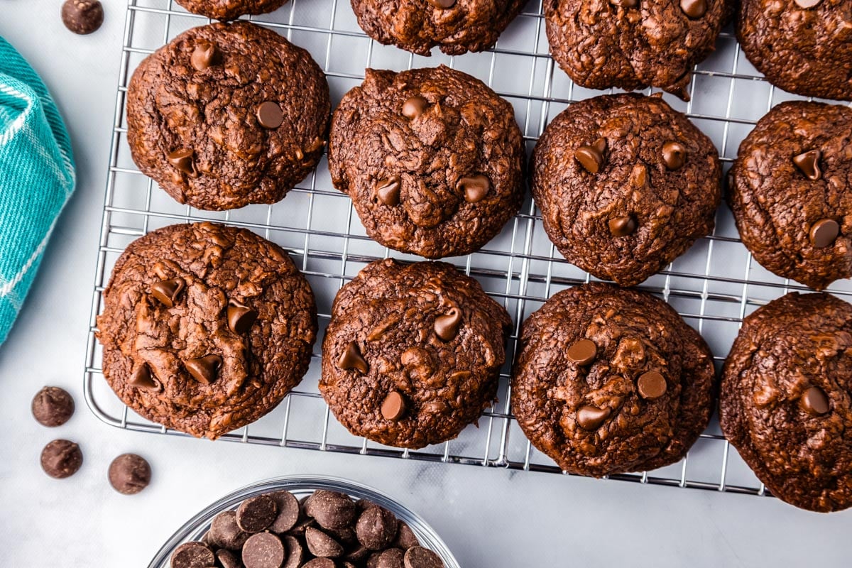 Cookies on a wire rack with chocolate chips surrounding them.