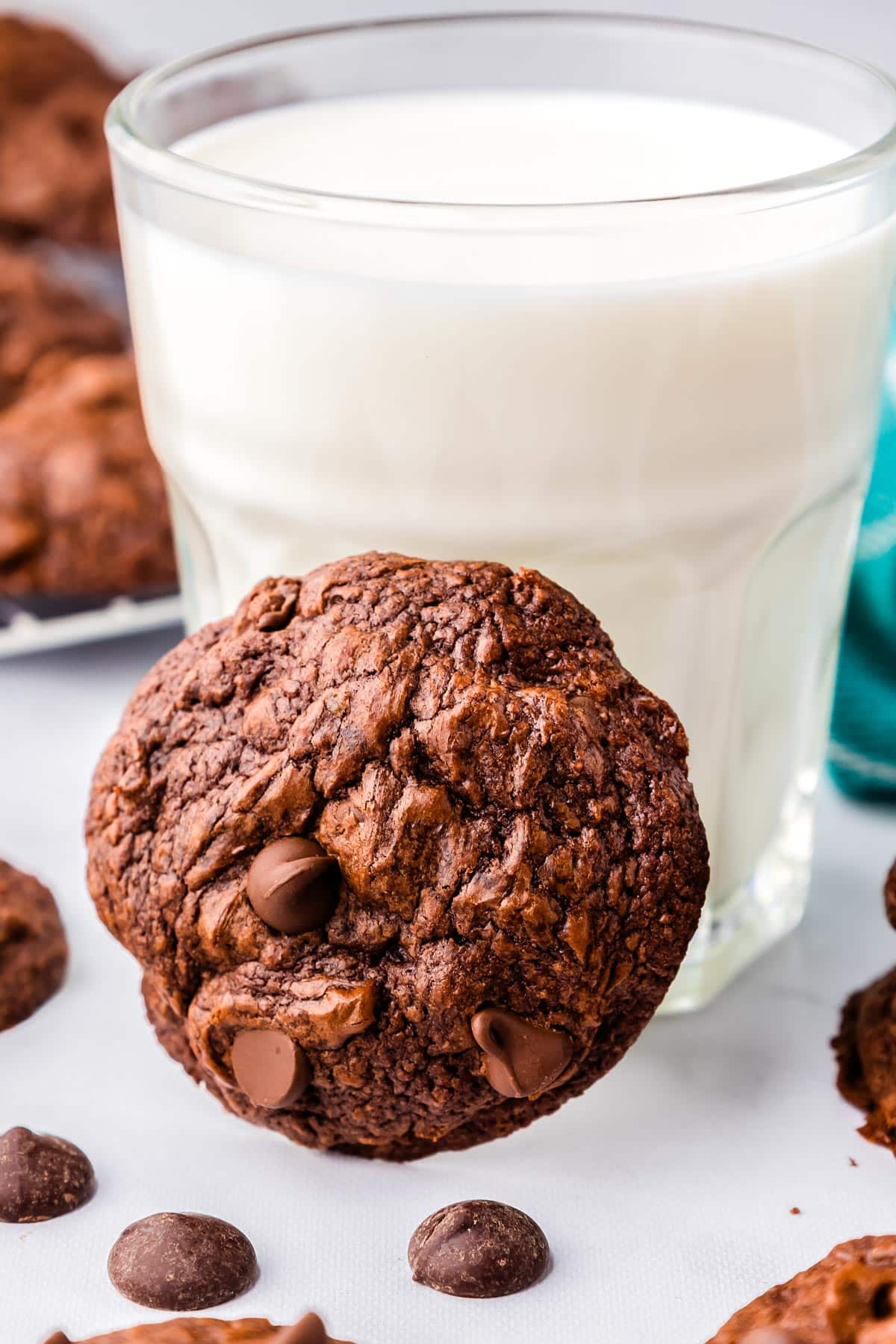 A Cookie leaning agains a glass of milk.