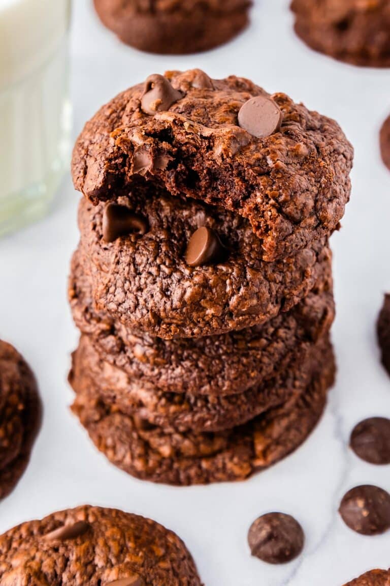 Five triple chocolate cookies staked on each other with a bite taken out of the top one.