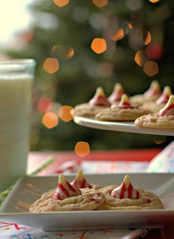 Peppermint cookies on a white plate with a lit Christmas tree in the background.