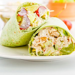 A close up picture of a Waldorf Chicken Salad Wrap cut in half and on a plate.