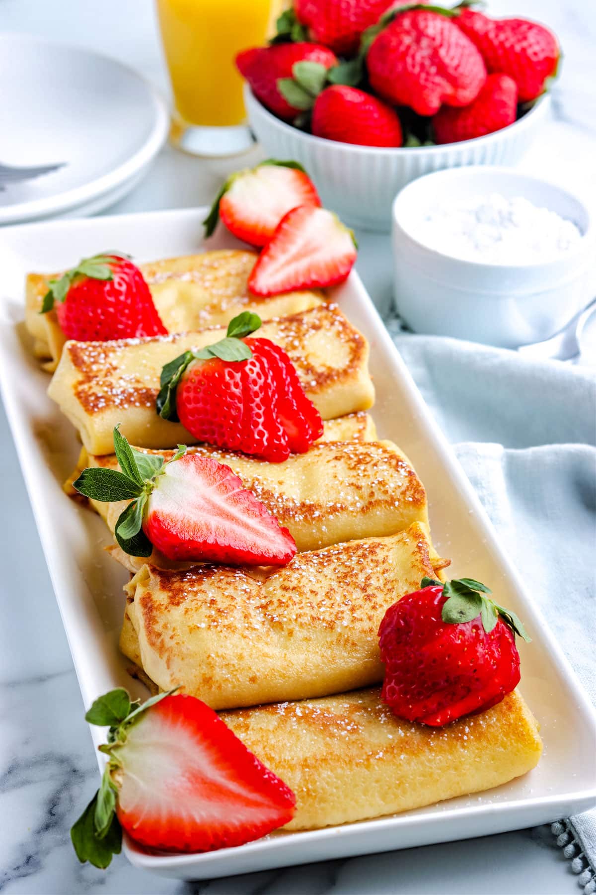 A picture of the finished blintzes on a serving dish with strawberries as a garnish.