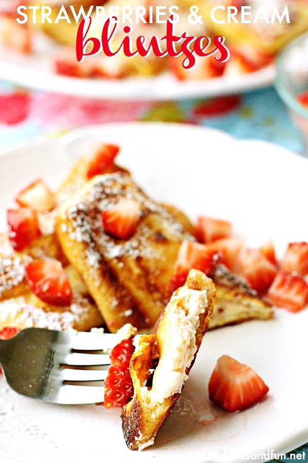 A close-up of a bite of Strawberries and Philly Cream Cheese Blintzes stuffed with a strawberry cream cheese filling, pan-fried and dusted with powdered sugar