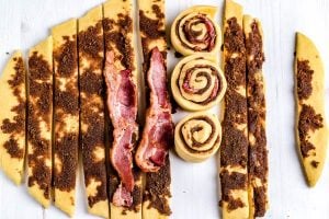 Place a piece of bacon onto each strip of dough and roll in buns.