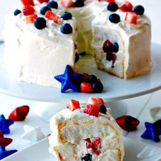 A slice of Patriotic Tunnel Cake on a plate with the remaining cake in the background on a cake stand