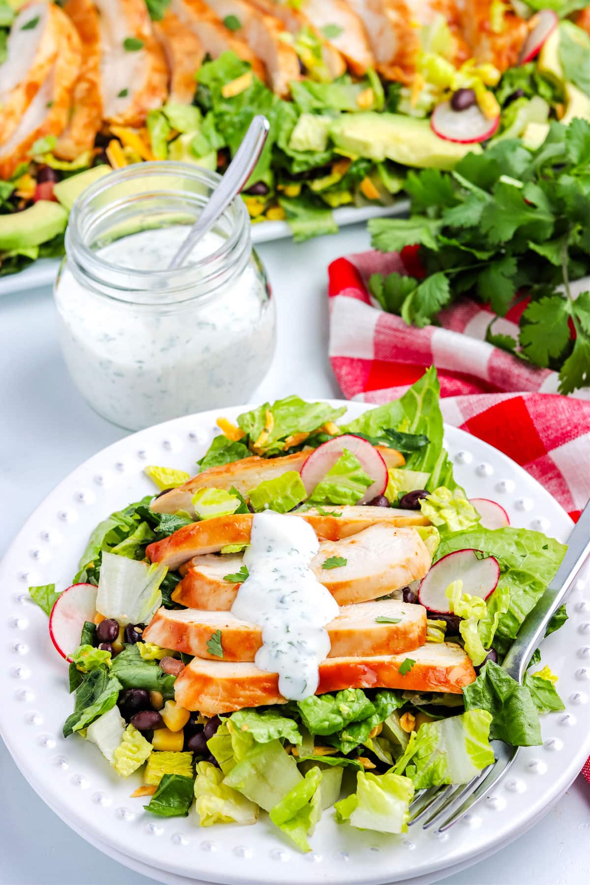 A picture of the salad on a plate with a jar of dressing in the background.