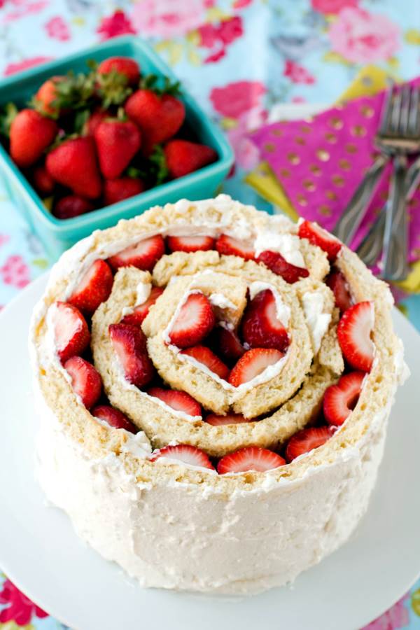 Roll Up cake with strawberries on a white cake pedestal.