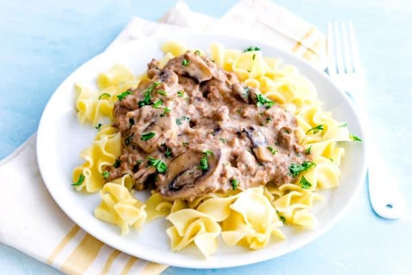 Quick and easy Ground Beef Stroganoff on a white plate over egg noodles.