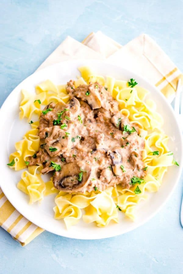 Ground Beef Stroganoff over egg noodles on a white plate.