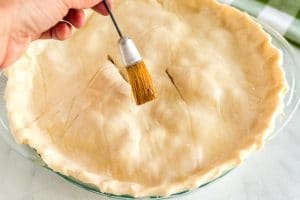 Brush the top pie crust with egg white.