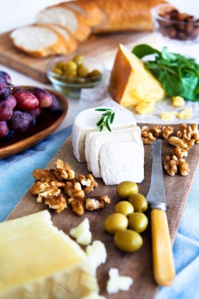 cheese, nuts, and olives on a wooden board. 