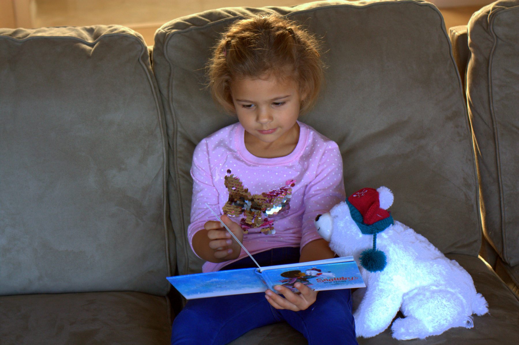 A little girl reading a story to a stuffed animal
