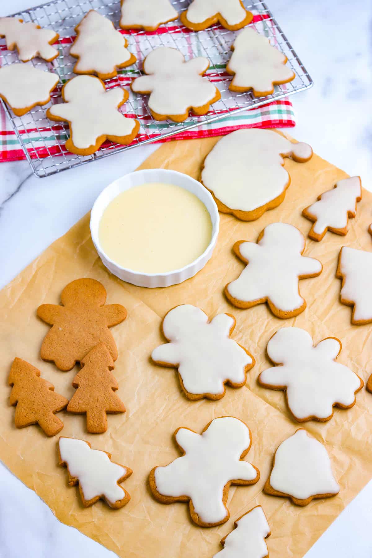 Orange gingerbread on a piece of parchment paper and most of them are dipped in an orange glaze.