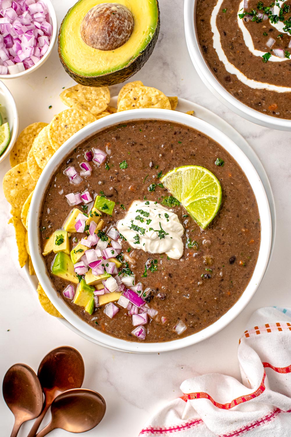 An overhead picture of Black Bean Soup in a white bowl with tortilla chips served with it.