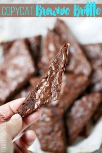 Brownie Brittle cut into piece and a hand holding a piece for a close up shot.