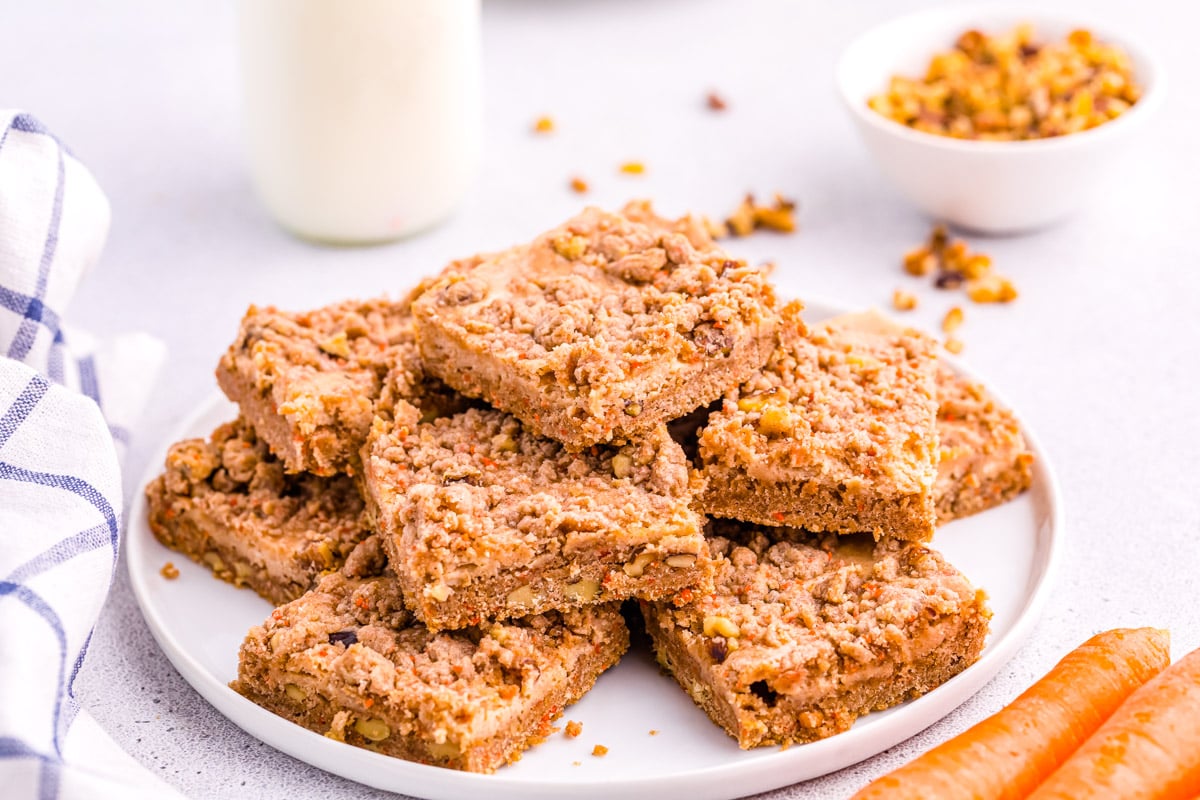 A pile of these carrot cake bars on a white plate.