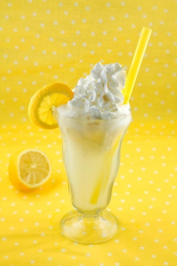 Lemon Cream Pie Float in a soda fountain glass with a pretty yellow background. 