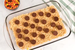 Pour half of the Rice Krispies mixture into the pan and lay the peanut butter cups on top.