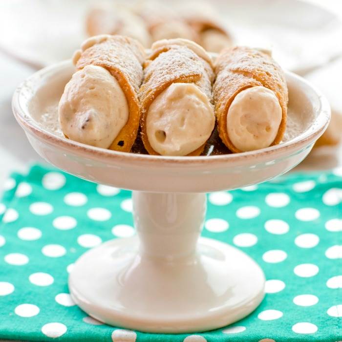 Cannoli shells and cream on a cake stand