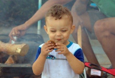 Little boy eating a chocolate chip cookie. 