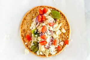 Place the chicken souvlaki mixture and toppings on the pita.