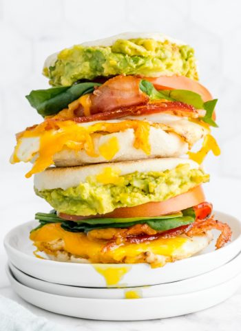 Two loaded Breakfast Sandwiches stacked on top of each other on a white plate.
