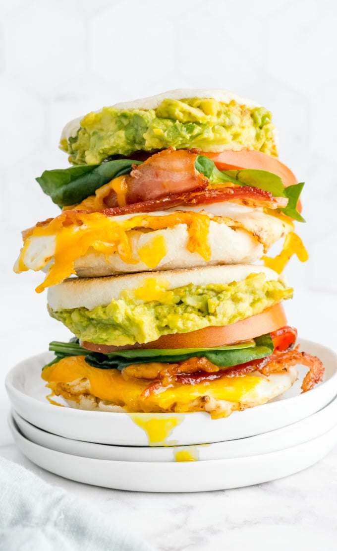 Two loaded Breakfast Sandwiches stacked on top of each other on a white plate.