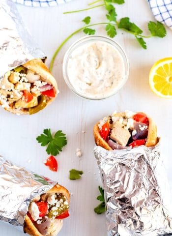 An overhead picture of 3 Chicken souvlaki pitas wrapped up in foil.