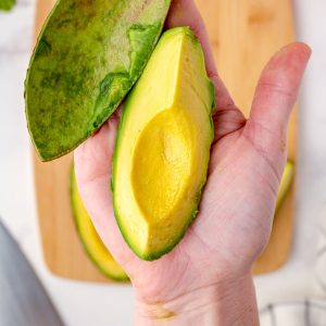 A close up picture of a cut and peeled avocado in a hand.