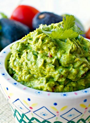 Guacamole in a serving bowl. with cilantro on top.